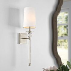 a wall light that is next to a vase with flowers on the table in front of it