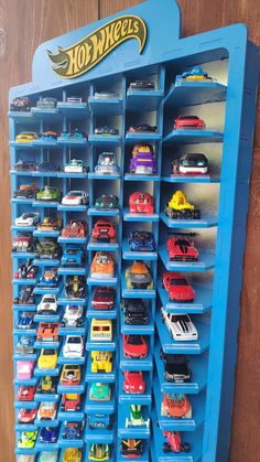 a blue toy display case filled with lots of hot wheels cars and trucks on shelves