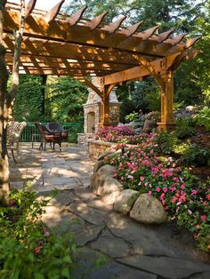 an outdoor patio with stone walkway and pergolated area, surrounded by trees and flowers