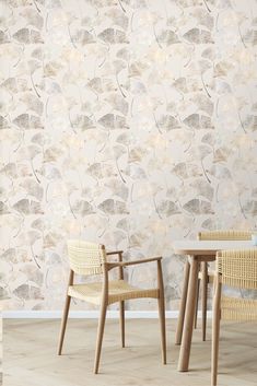 two chairs and a table in front of a wall with flowers on the wallpaper