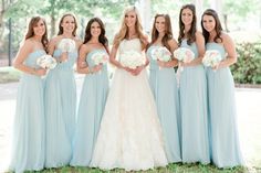 a group of women standing next to each other holding bouquets in front of them