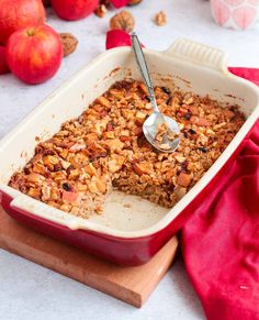 a red casserole dish filled with granola and topped with a serving spoon