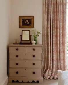 a dresser with drawers and a mirror on top of it next to a window covered in curtains