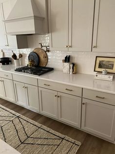 a kitchen with white cabinets and gold trim on the counter tops, along with an area rug