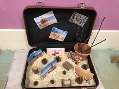 an open suitcase filled with pictures and cards on the floor next to a potted plant