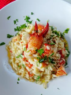 a white plate topped with rice covered in shrimp and garnished with parsley