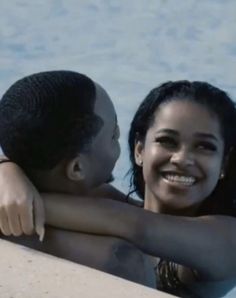 a woman and a boy are in the water smiling at each other while they both have their arms around one another