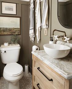 a white toilet sitting next to a sink in a bathroom under a mirror on a wall