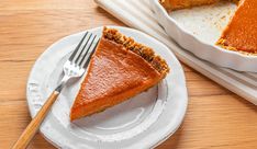 a slice of pumpkin pie on a white plate with a fork next to the pie