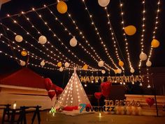 an outdoor birthday party with balloons and lights on the ceiling, decorated in white and yellow colors