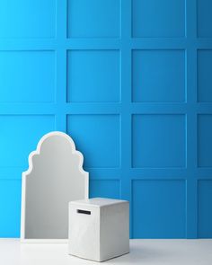 a white box sitting on top of a table next to a blue wall and mirror