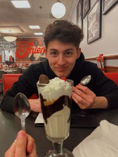 a man sitting at a table with an ice cream sundae in front of him