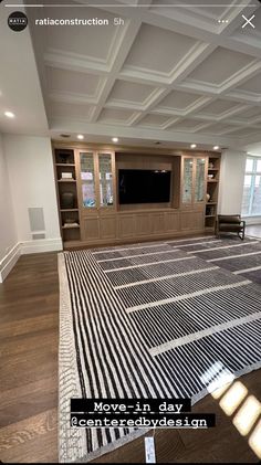 an empty room with a large rug on the floor in front of a flat screen tv