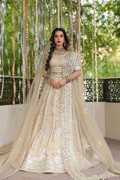 a woman in a white and gold lehenga with long veil on her head