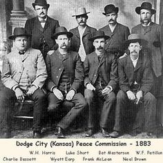 an old black and white photo of men in suits and hats posing for the camera