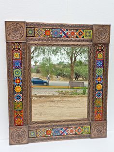 a mirror that is on the side of a wall with a car parked in front of it