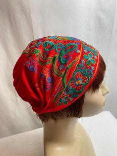 a mannequin head wearing a red hat with colorful paisley designs on it's side