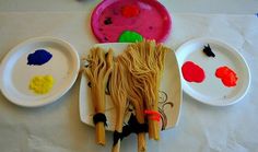 the table is covered with plates and bowls filled with different types of art materials, including noodles