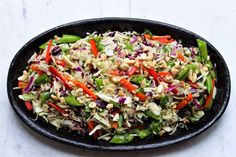 a black bowl filled with coleslaw and carrots on top of a table