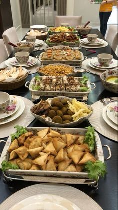 a table filled with lots of food on top of white plates and silver trays