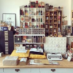 a desk with many items on it in a room filled with books and other things