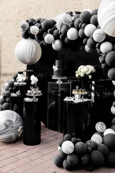 black and white balloons are on display in front of a fireplace with vases filled with flowers