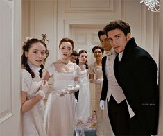 a group of people standing around each other in formal dress and tuxedo attire