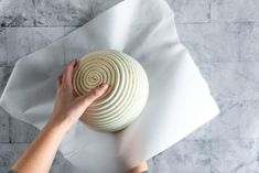 a person holding a white object on top of a paper towel next to a marble wall