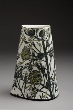 a black and white vase with flowers on it's side, in front of a gray background