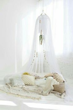 a bed with white sheets, pillows and blankets on top of it in front of a window