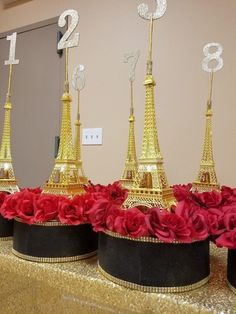 the table is set up with gold and red flowers in front of the eiffel tower