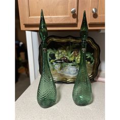 two green glass vases sitting on top of a counter