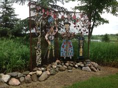 an iron gate with decorative items on it in the middle of a grassy area next to some trees