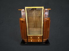 an old fashioned wooden cabinet with glass doors on it's front and side panels