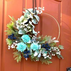 a wreath with blue flowers and greenery hangs on the front door's red door