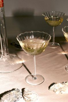 three wine glasses filled with white wine and cookies on a table next to each other