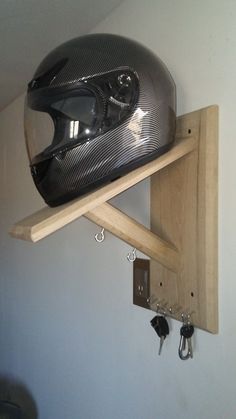 a motorcycle helmet mounted to the side of a wooden shelf with key hooks on it