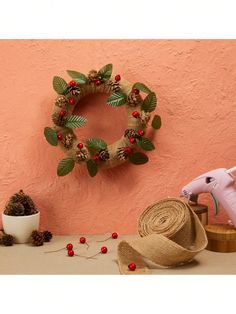 a pink wall with a wreath on it and other items around it, including a straw hat