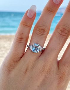 a woman's hand with a ring on the beach