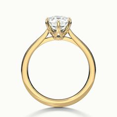 a yellow gold engagement ring with a single diamond in the center, on a white background