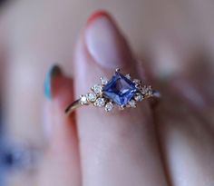 a woman's hand holding a ring with a tan diamond and blue sapphire in it