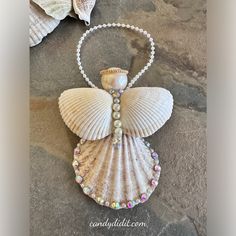 a necklace with an angel made out of seashells and pearls on a stone surface