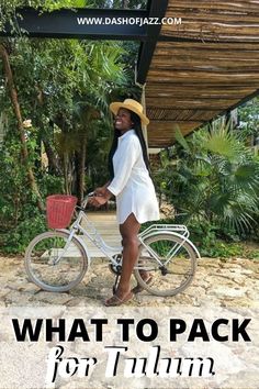 a woman in a white dress and straw hat riding a bicycle