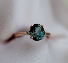 a ring with an oval cut blue diamond in it on a white cloth, close up