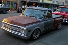 an old pickup truck parked on the side of the road in front of other cars