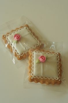 two decorated cookies sitting on top of each other in plastic wrappers with pink flowers