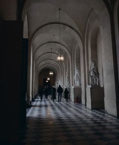 people are walking down the hallway in an old building with black and white checkered floors