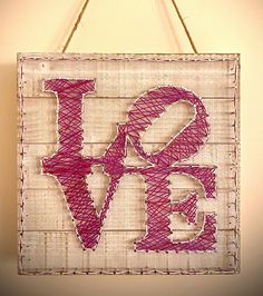 a string art love sign hanging on a wall