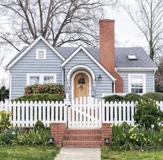 a blue house with white picket fence and flowers