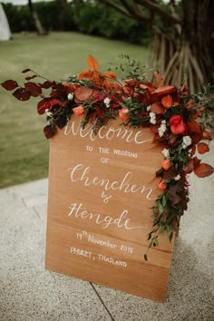 a welcome sign is adorned with flowers and greenery